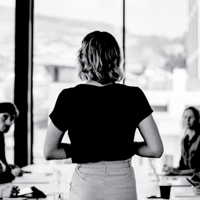 Back of woman standing and presenting in an office